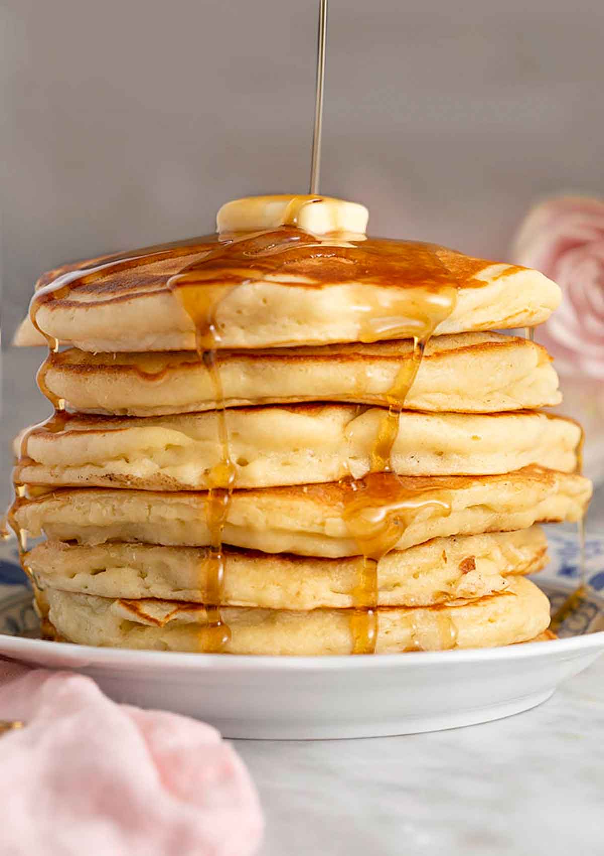Stack of pancakes topped butter and maple syrup.